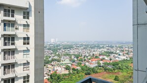 A high-rise building with multiple balconies and a view of a residential area with houses and greenery. - Clean And Nice 1Br At Apartment Casa De Parco (Tangerang)