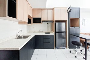 Una cocina moderna con microondas integrado, refrigerador de acero inoxidable y encimera negra.