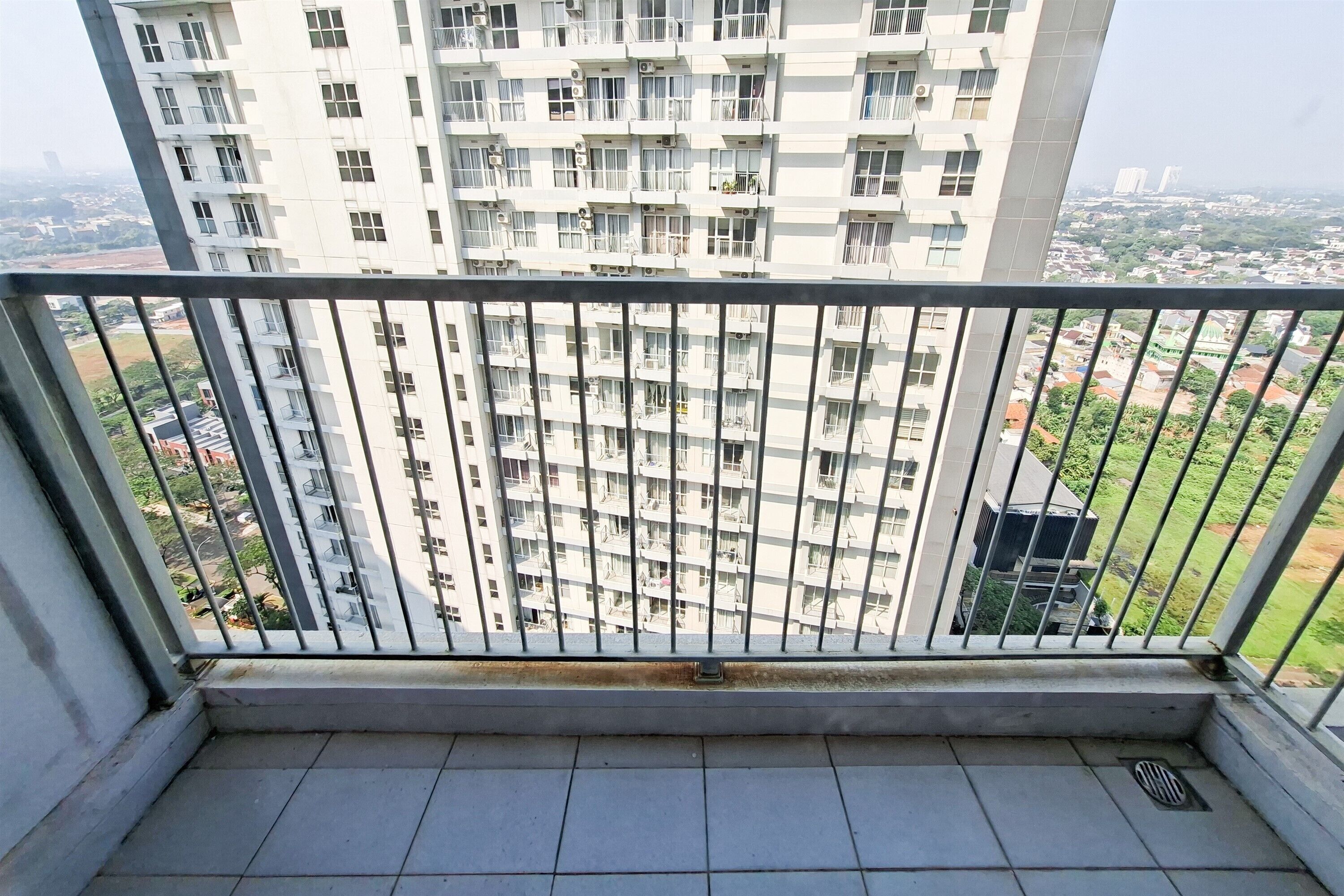 A balcony with a metal railing overlooking a residential area with multiple-story buildings.