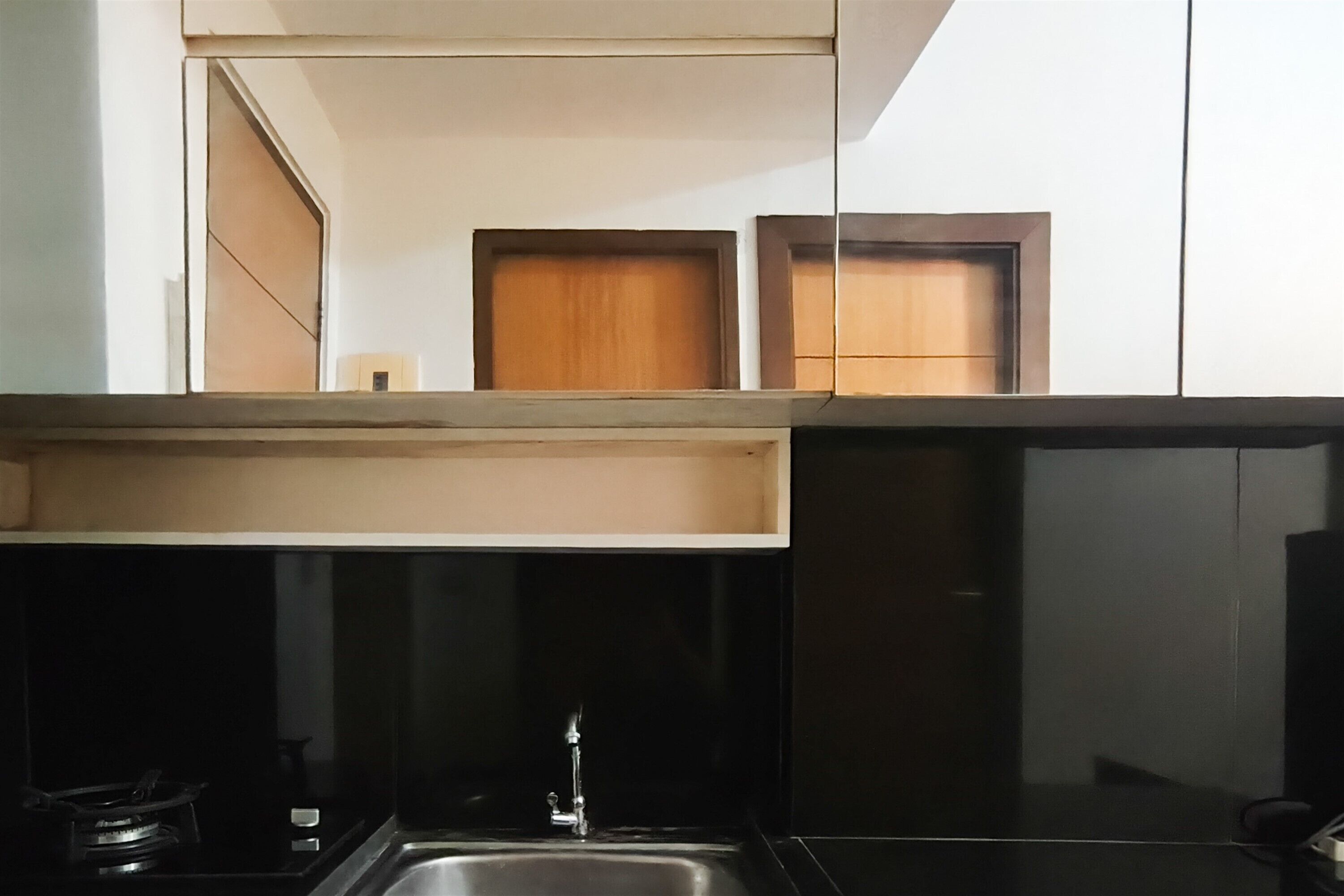 A kitchen with a black countertop, a stainless steel sink, and wooden cabinets above.
