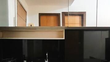 A kitchen with a black countertop, a stainless steel sink, and wooden cabinets above.