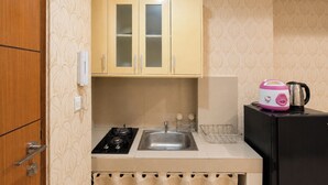 Eine kleine Küche mit Gaskochfeld, Spüle und einem kleinen Kühlschrank.