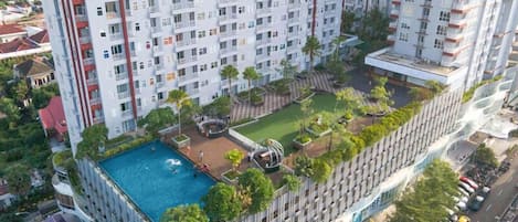 Un edificio de gran altura con piscina en la azotea, terrazas ajardinadas y un diseño arquitectónico moderno.