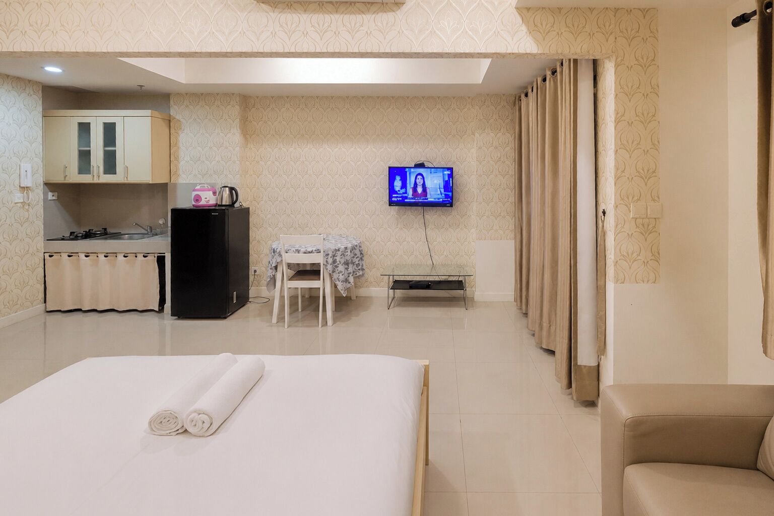 Een hotelkamer met een bed, een bureau, een stoel, een televisie en een kitchenette.