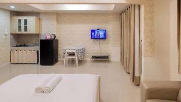 Een hotelkamer met een bed, een bureau, een stoel, een televisie en een kitchenette.