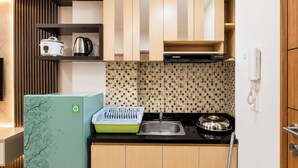 A compact kitchen with a refrigerator, a kettle, a coffee maker, a microwave, and a sink. - Functional With Minimalist Design 2Br At Vida View Makassar Apartment (Makassar)