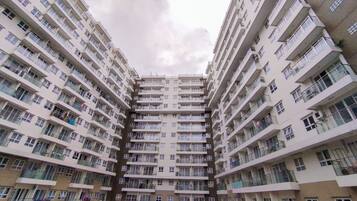 A multi-story residential building with balconies, a central courtyard, and parked cars.