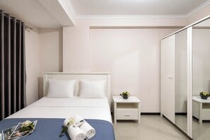 Una habitación de hotel con cama, mesitas de noche, un espejo y un armario.