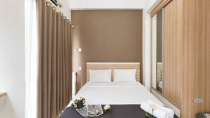 Ein Hotelzimmer mit Bett, Spiegel, Kleiderschrank und einem Fenster mit Vorhängen.