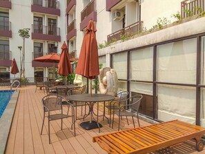 Ein Poolbereich mit Sitzgelegenheiten im Freien, darunter Tische und Stühle sowie Sonnenschirme.