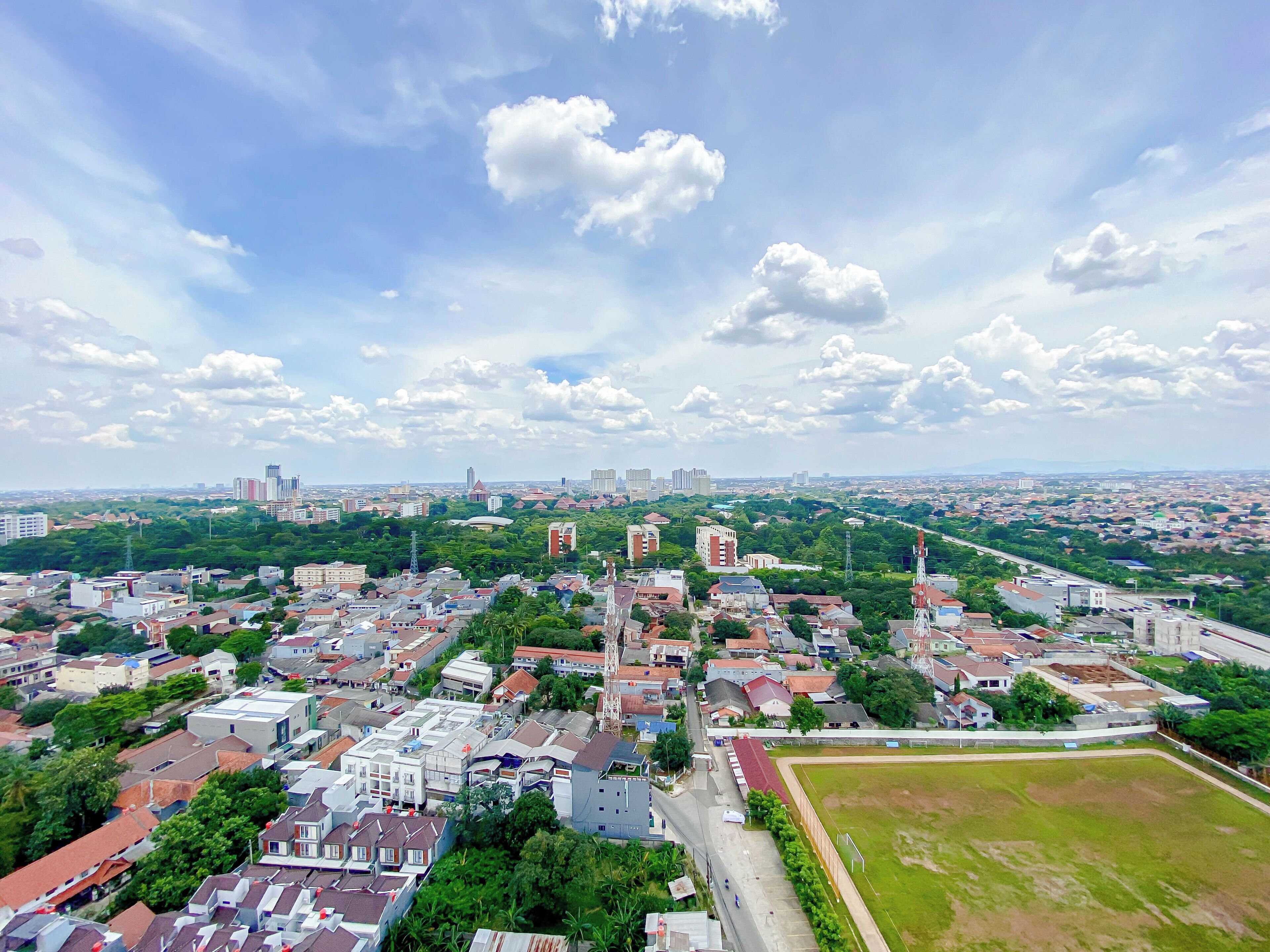 An aerial view of a cityscape with buildings, roads, and green spaces.