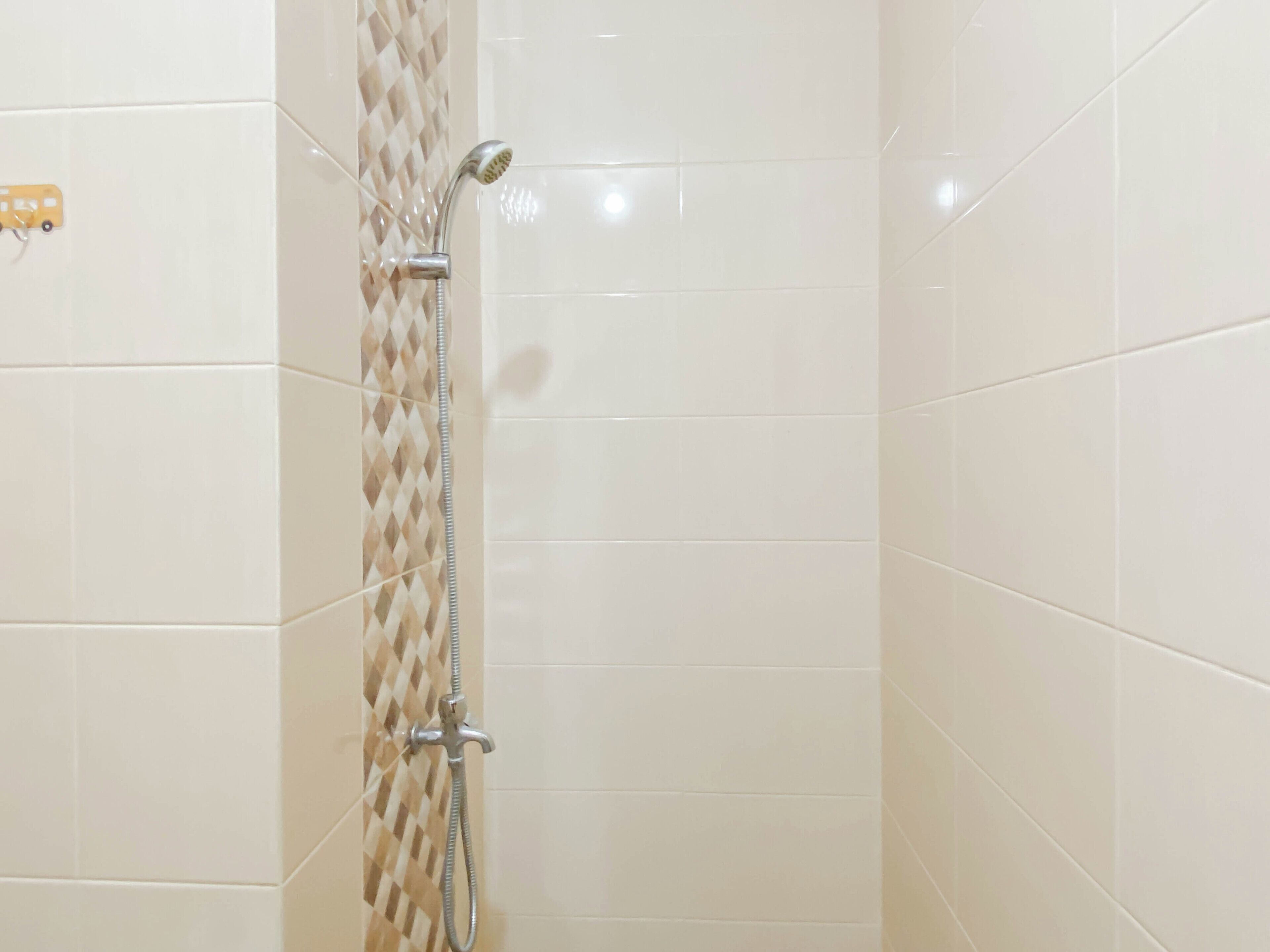 A shower with a handheld showerhead and a wall-mounted faucet.