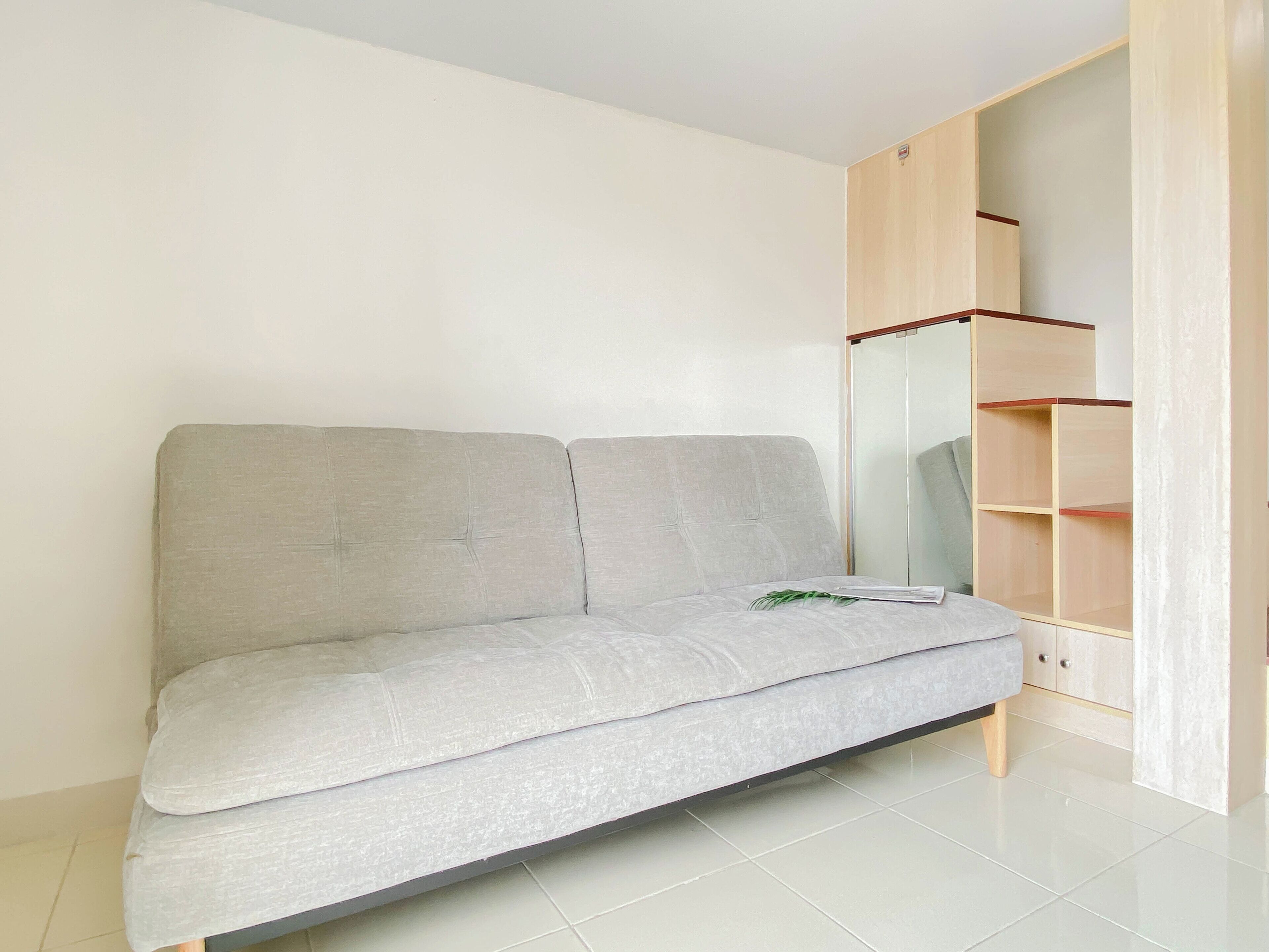 A modern living room with a grey sofa, a wooden cabinet, and a glass door.
