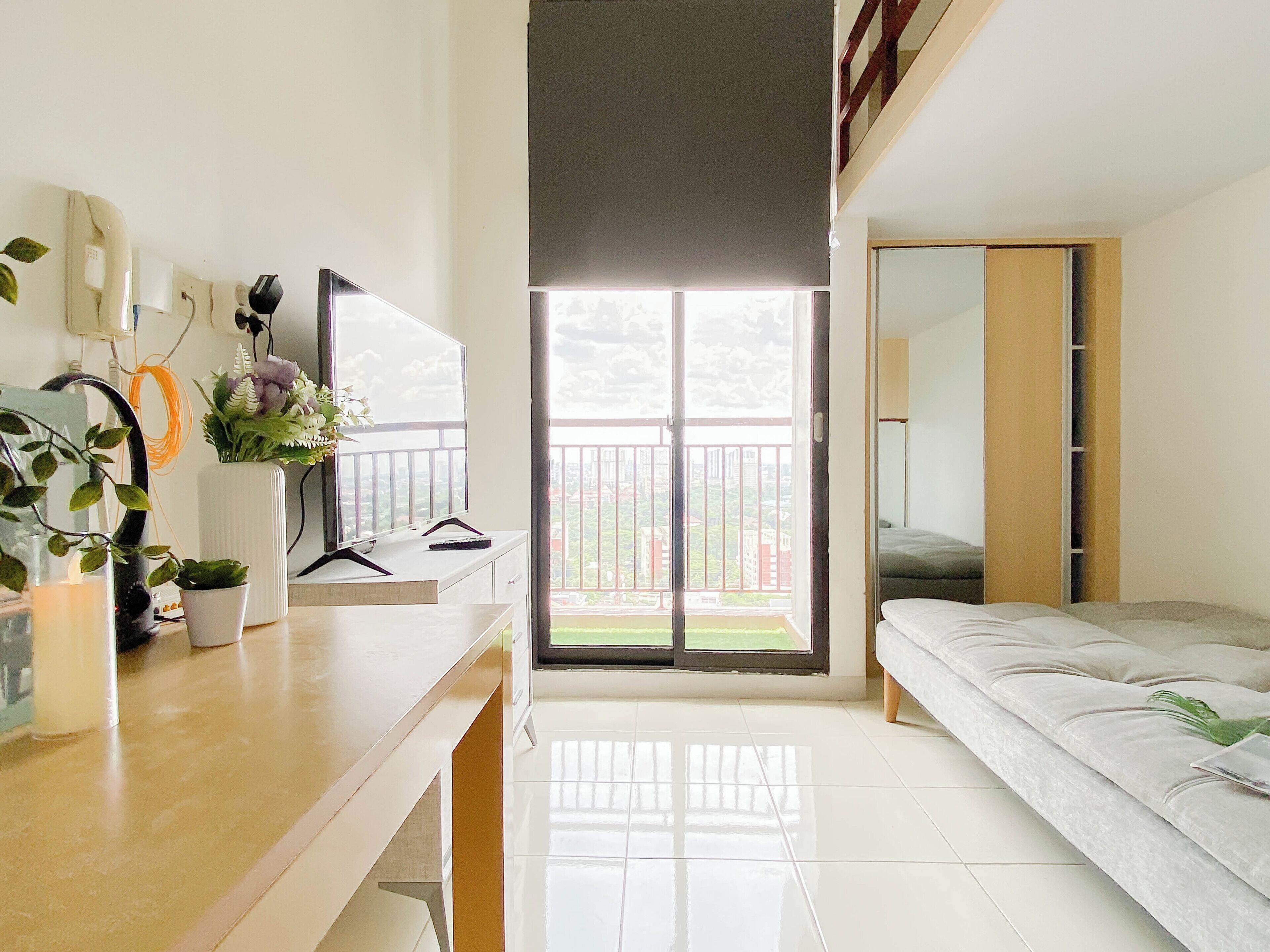Ein modernes Schlafzimmer mit Bett, Schreibtisch, Spiegel und einem Balkon mit Blick.