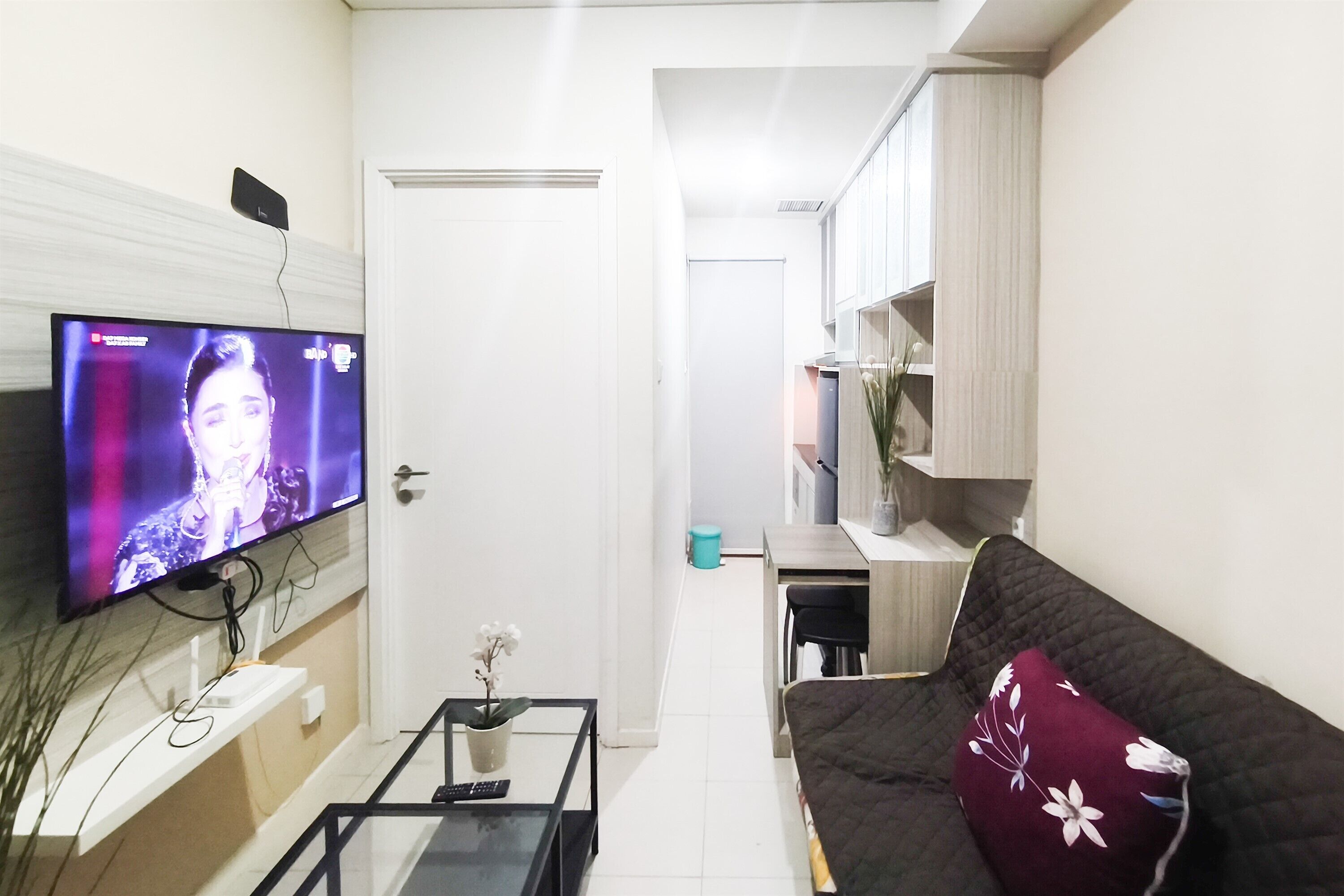 Ein Wohnzimmer mit Flachbildfernseher, einer Couch, einem Couchtisch und einer kleinen Pflanze.