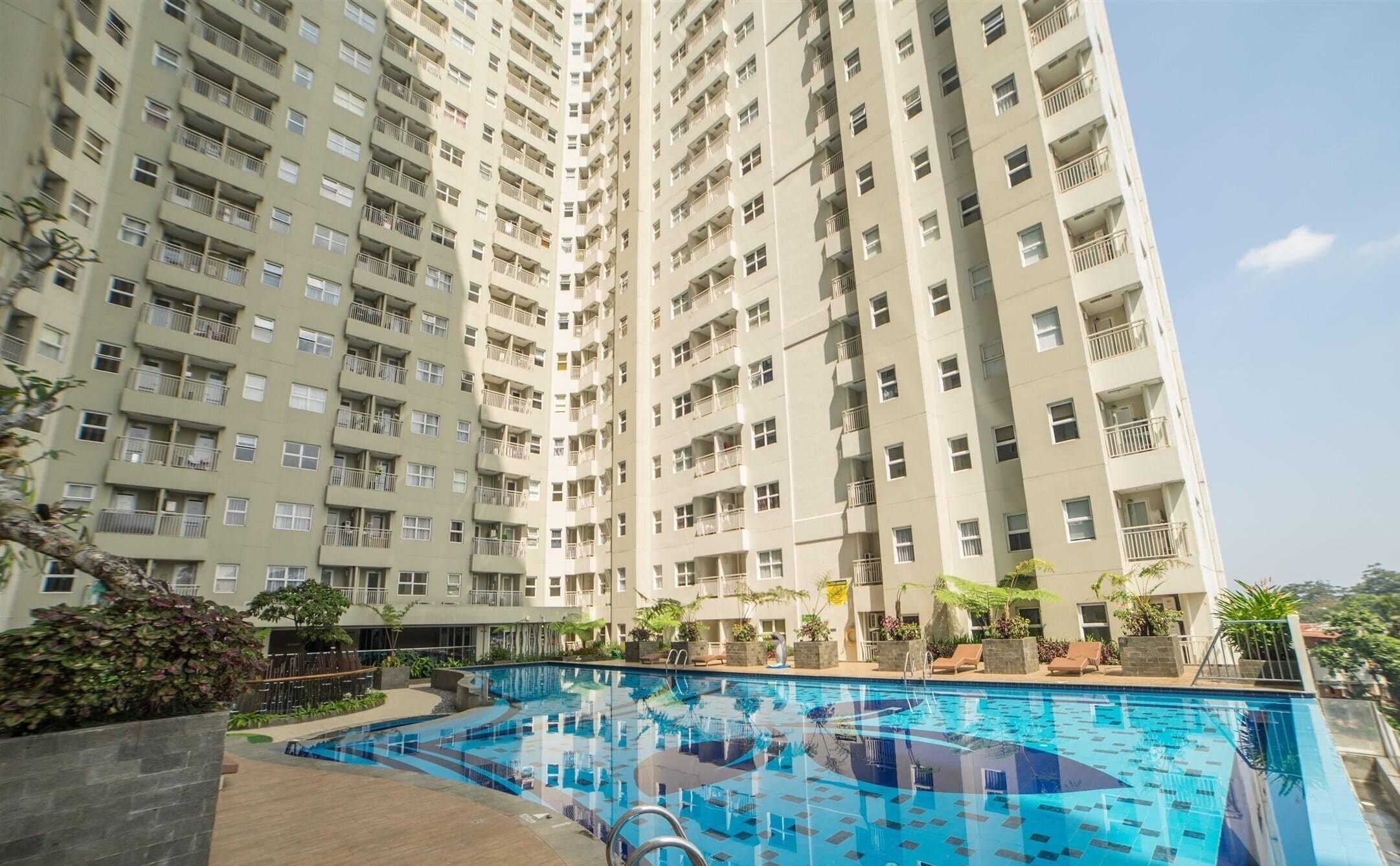 A high-rise residential building with a swimming pool in the foreground.