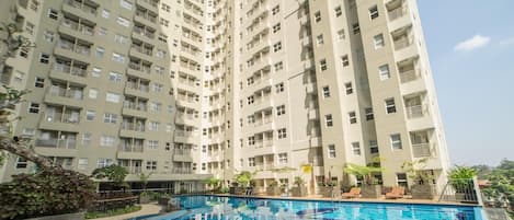 A high-rise residential building with a swimming pool in the foreground.