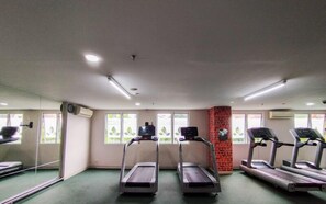 Ein Fitnessstudio mit Laufbändern, einer Ziegelstütze und großen Fenstern.