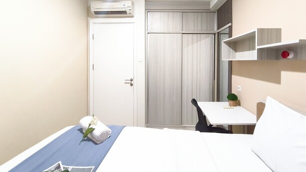 Camera d'albergo con un letto, una scrivania, una sedia, un tavolino con una pianta e un armadio.