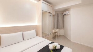 Habitación de hotel con cama, escritorio, armario y unidad de aire acondicionado.