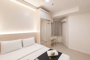 Ein Hotelzimmer mit Bett, Schreibtisch, Kleiderschrank und Klimaanlage.