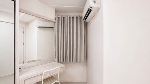 Una habitación pequeña y limpia con escritorio, silla y aire acondicionado.