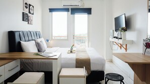 A hotel room with a bed, desk, chair, and TV. - Comfortable Living Studio At Apartment Sentul Tower (Bogor)