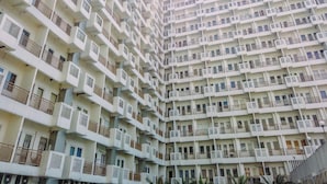 A high-rise residential building with multiple balconies, air conditioning units, and a uniform architectural design. - Comfortable Living Studio At Apartment Sentul Tower (Bogor)