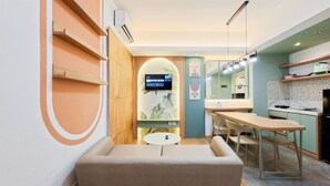 A modern hotel room with a sofa, a small table, a TV, and a kitchenette. - Modern 3Br Apartment With Chic Style At M-Town Residence (Tangerang)