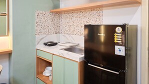 A compact kitchen with a stainless steel refrigerator, a sink, and a countertop with a dish rack. - Modern 3Br Apartment With Chic Style At M-Town Residence (Tangerang)