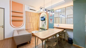 A modern room with a sofa, a table, chairs, a TV, and a mirror. - Modern 3Br Apartment With Chic Style At M-Town Residence (Tangerang)