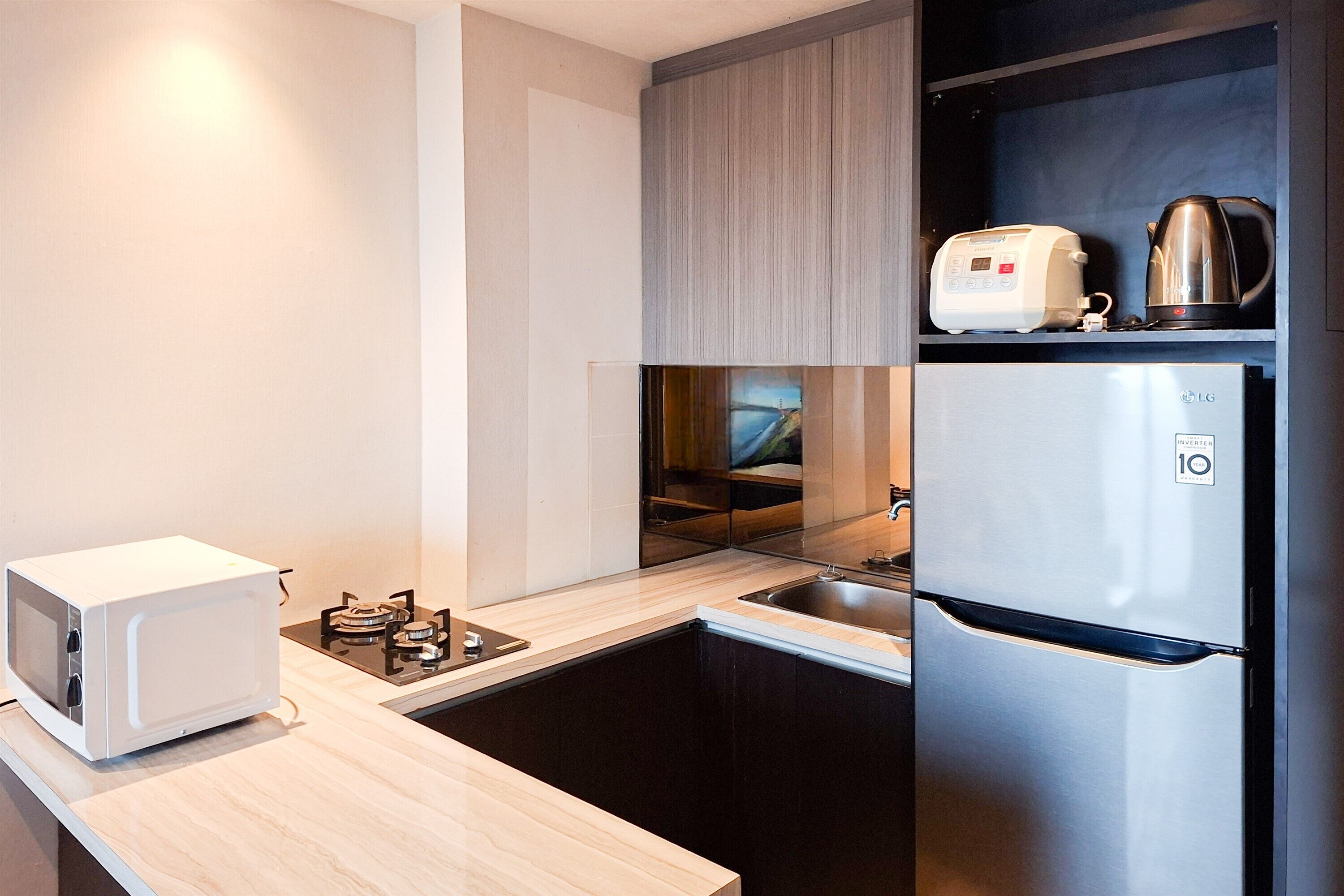 A modern kitchen with a microwave, toaster, kettle, and refrigerator.