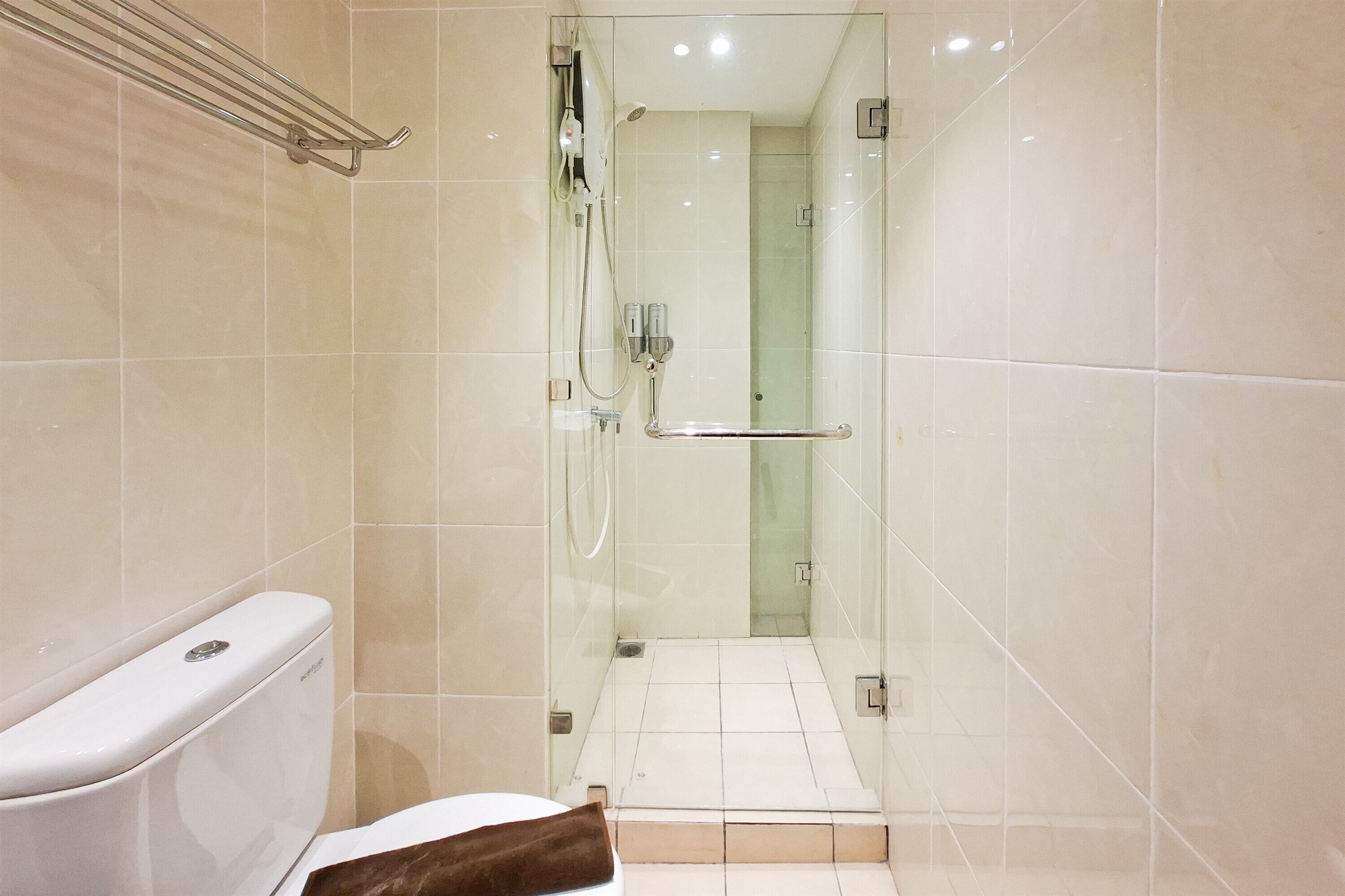 Un baño con ducha de vidrio, inodoro blanco y barra para toallas.