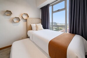 Une chambre d’hôtel avec un lit, une fenêtre avec des rideaux et une vue sur la ville.