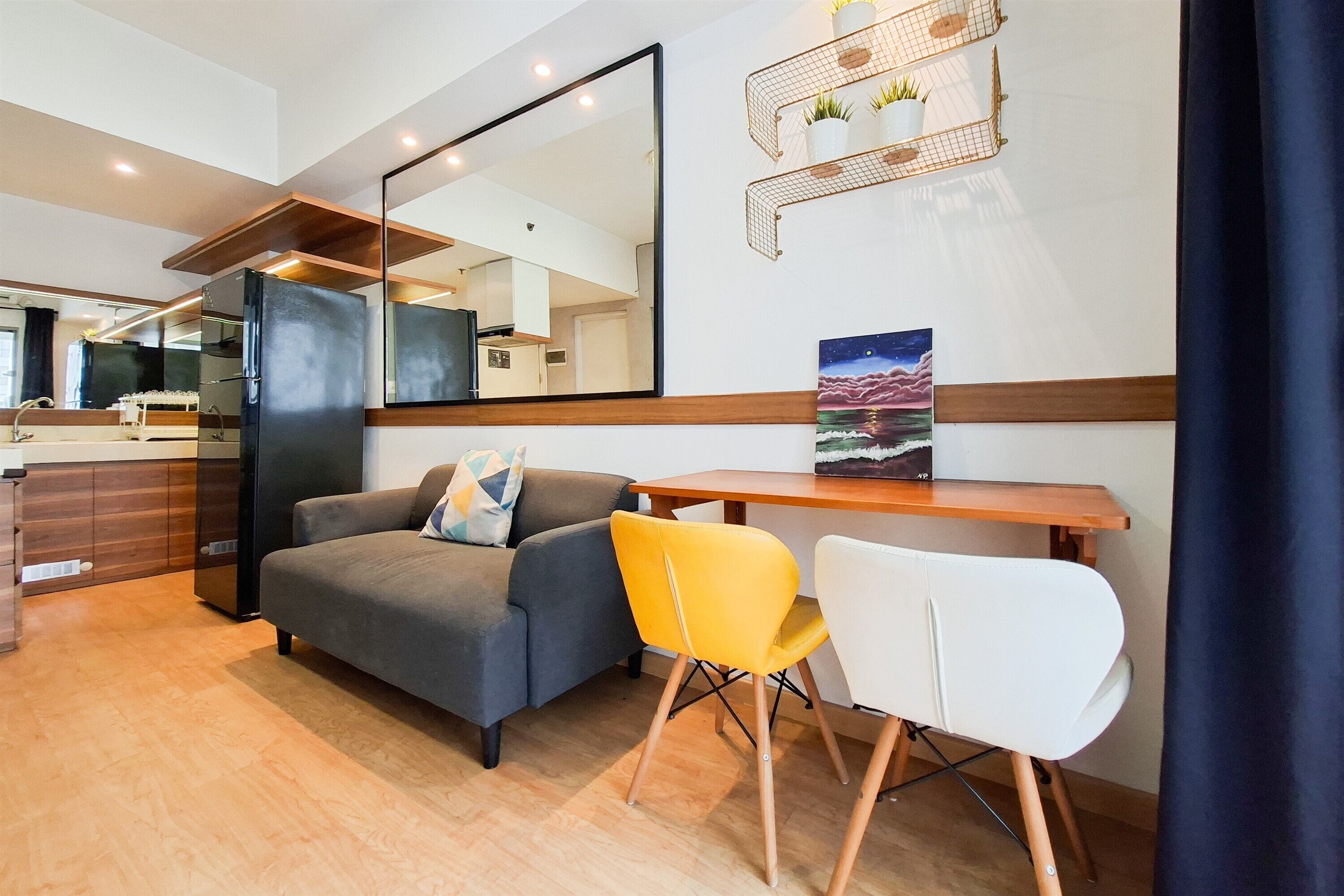 Un salon moderne avec un canapé, une table à manger, une chaise jaune, une chaise blanche et un tableau accroché au mur.