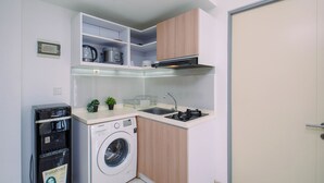 A compact kitchen with a washing machine, a microwave, and a sink. - Neat And Comfortable 1Br At Apartment M-Town Residence (Tangerang)