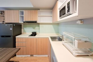 Eine kompakte Küche mit Holzschränken, einem Edelstahlkühlschrank, einer Mikrowelle und einem eingebauten Geschirrspüler.