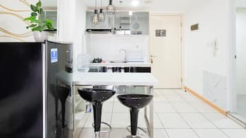 Una cocina moderna con refrigerador, dos taburetes de bar, un lavamanos y una planta en maceta.