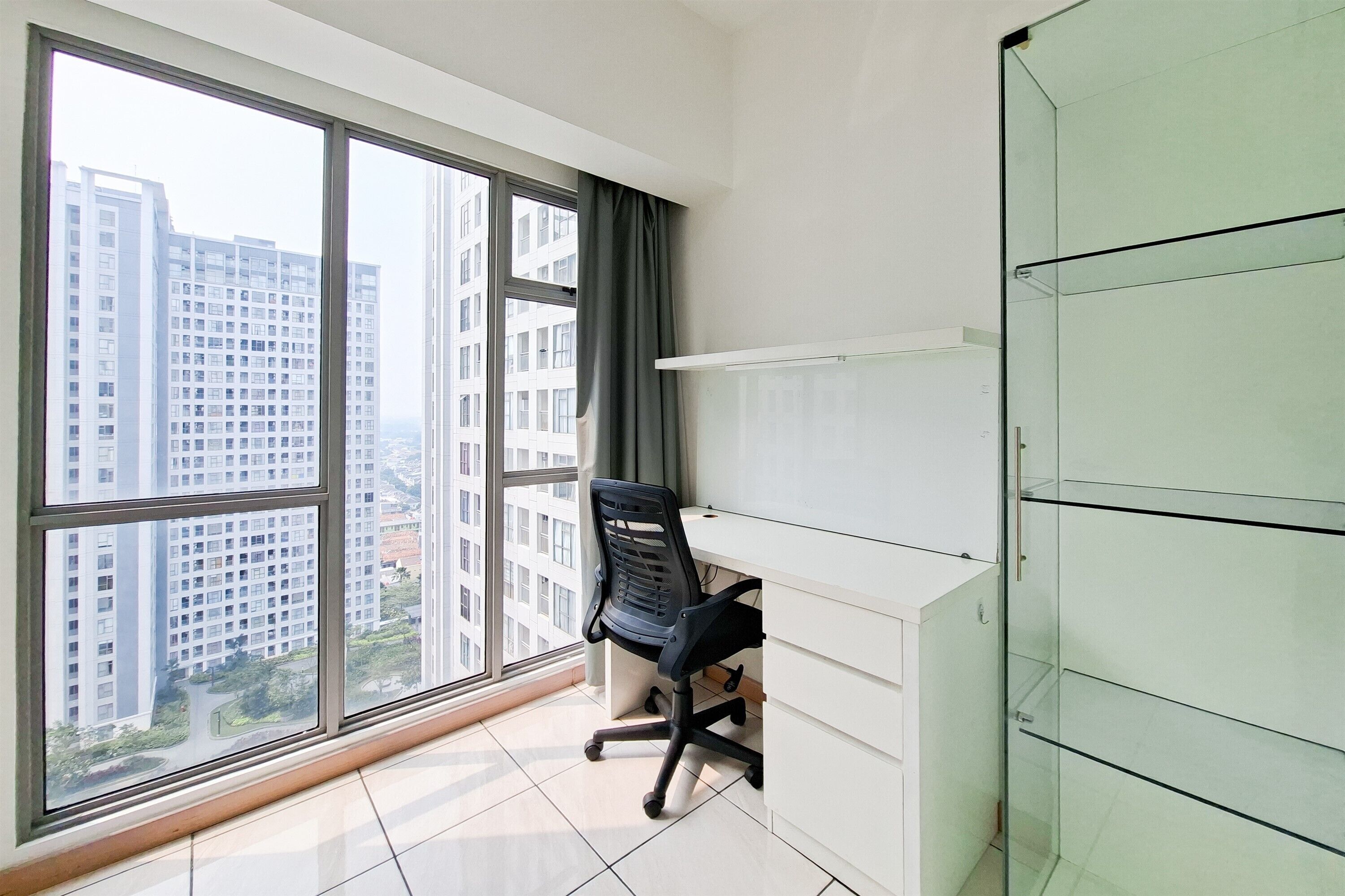 A room with a large window, a desk, a chair, and a glass cabinet.