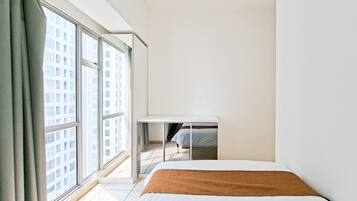 Une chambre d’hôtel au design minimaliste, dotée d’une grande fenêtre, d’un lit et d’un petit bureau.