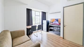 Una sala de estar con sofá, televisión, escritorio y sillas, y una puerta.