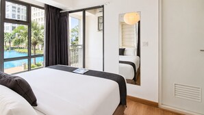 Hotellihuone, jossa on suuri sänky, näköala uima-altaalle ja parveke, jossa on verhot.