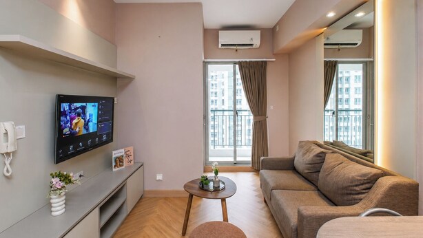 Uma sala de estar moderna com uma televisão de tela plana, um sofá, uma mesinha de centro e uma varanda com vista para edifícios.