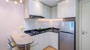Uma cozinha compacta com bancada de mármore, eletrodomésticos de aço inoxidável e um espaço de refeições com mesa e cadeiras.