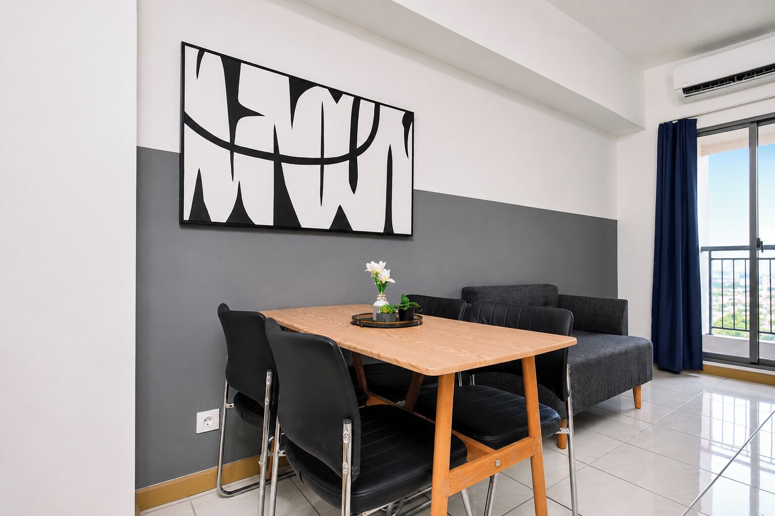 A modern dining area with a wooden table, black chairs, and a grey sofa.