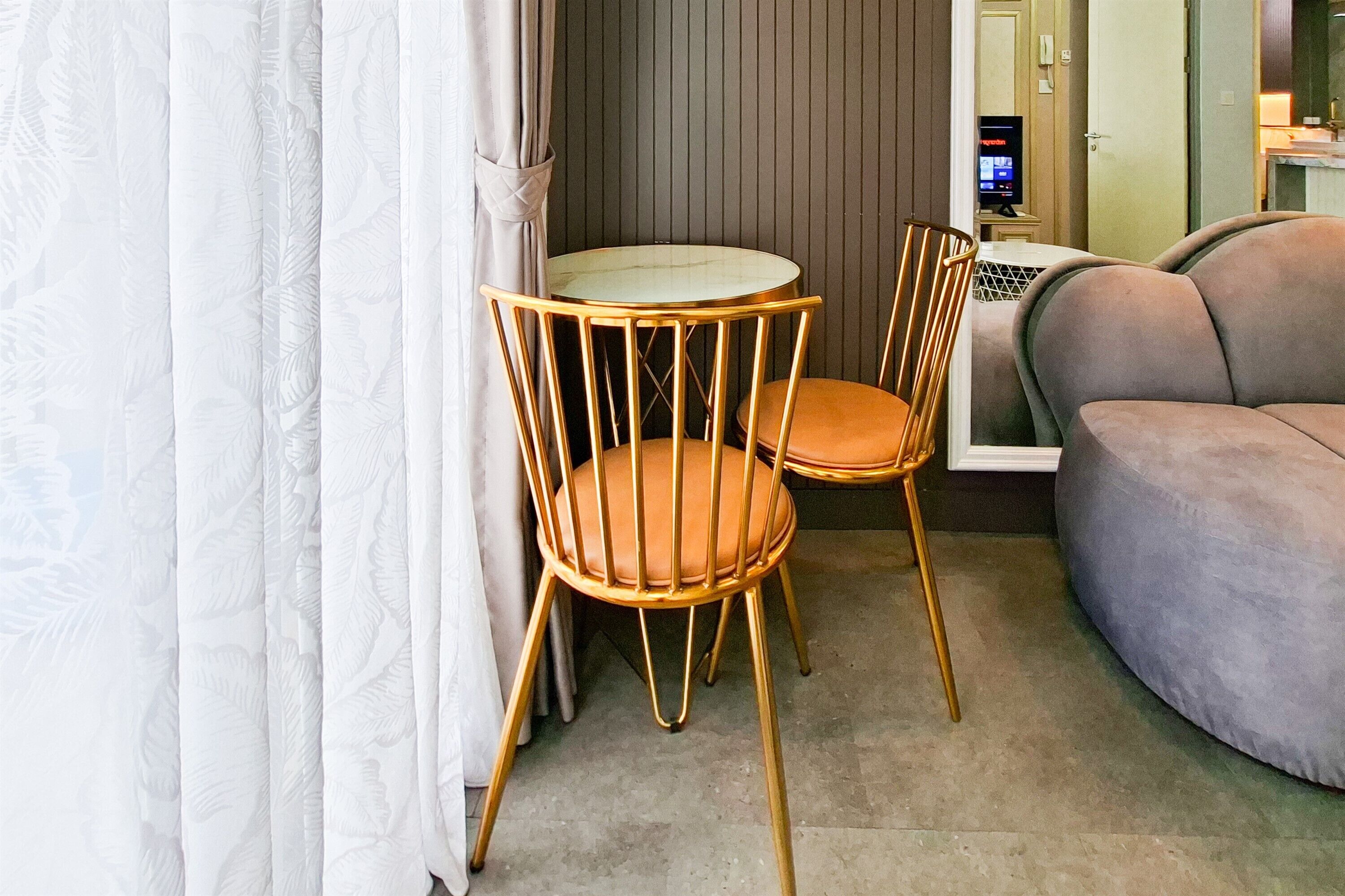 A room with a round table, two chairs, a sofa, and a television.
