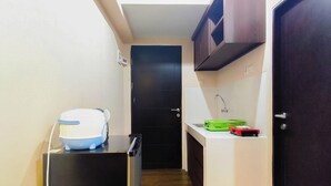 Una cucina compatta con frigorifero, microonde, lavello e un piano di lavoro con scolapiatti verde.