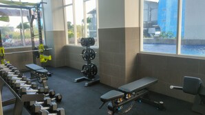 Una palestra con attrezzature per sollevamento pesi, una panca e ampie finestre.