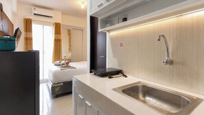 Ett modernt hotellrum med ett litet kök, en säng och ett badrum med dusch.