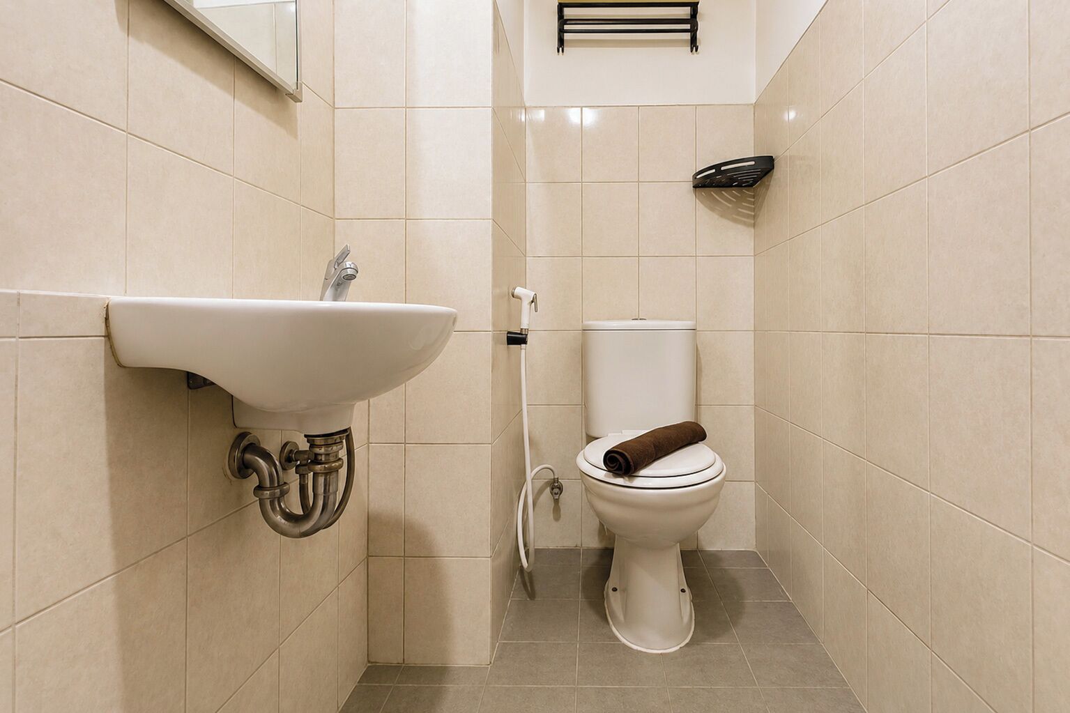Un bagno con un lavandino bianco, un water e un portascopevoli.